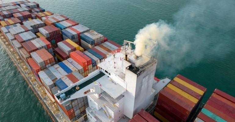 Exhaust fumes rising from a container ship funnel
