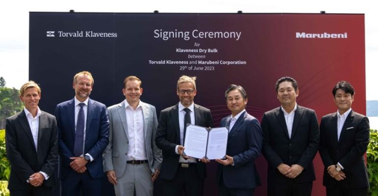 Company representatives at the singing ceremony, holding the signed agreement in front of a branded board