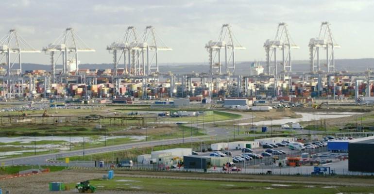 DP World's London Gateway cranes in far distance, vehicles, containers and grass verges in the fore