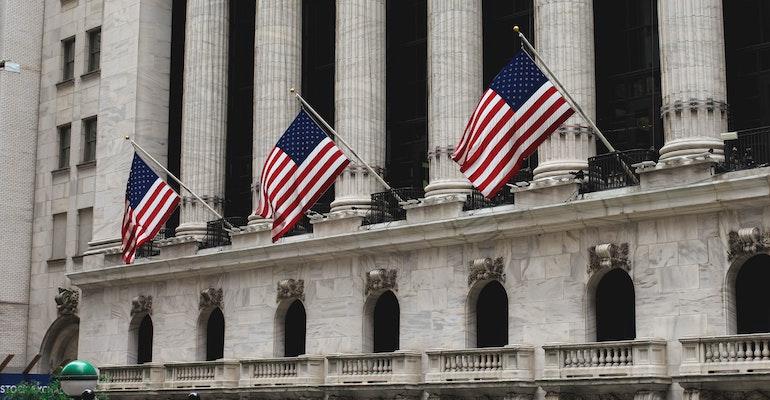 Wall St in New York with American flags
