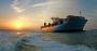 Container ship on ocean at sunset or sunrise.