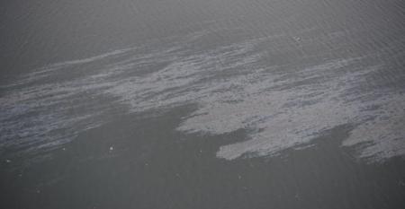 An oil spill in water seen from above
